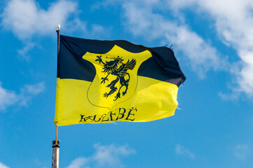 Kashubia flag with coat of arms of Kaszebe on blue sky.