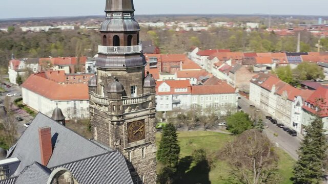 Drone flight up and around the town hall of Wittenberge in Brandenburg Germany. You can see residential buildings with red roofs.