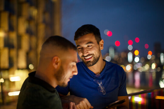 Happy men with smart phone in city at night