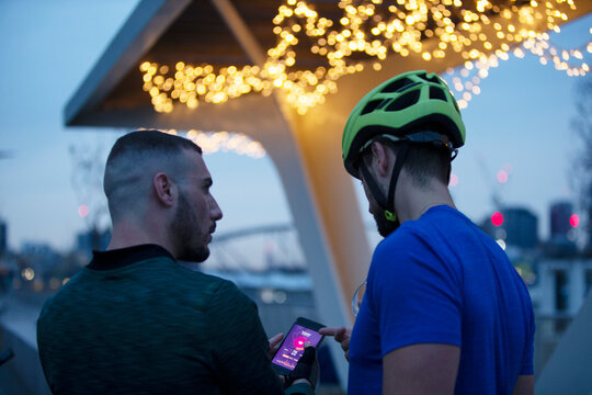 Men with smart phone under illuminated bridge at night