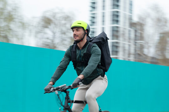 Male courier riding bike in city