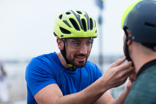 Man helping friend with bike helmet