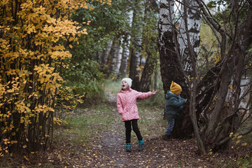 Naklejka na ściany i meble Little caucasian children in the autumn forest among trees