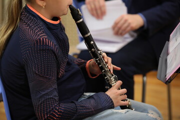 Fototapeta premium Girl student playing clarinet on notes musical instrument close-up on fuzzy background teacher