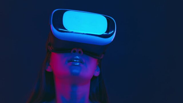 Augmented reality world. Excited asian lady in vr headset looking around, playing virtual video game in neon lights