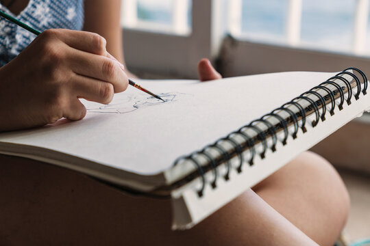 Female artist sketching near window