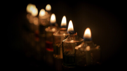 Colorful Hanukkah Chanukah Menorah oil candles burn against dark background
