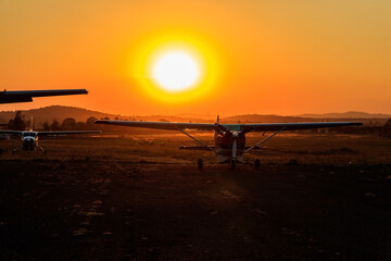 Fototapeta na wymiar Small propeller airplanes at sunset in Arusha airport, Tanzania