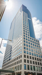 Fototapeta na wymiar Tall urban skyscraper rises up to clear sunny blue sky in downtown Denver, Colorado