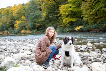 Naklejka na ściany i meble woman with dog enjoying autumn nature by the lake