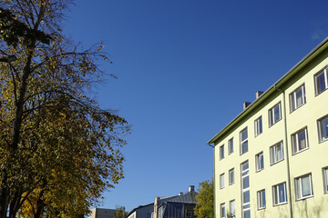 Close up of the yellow house. Clear blue sky background with some autumn foliage on the left. Bottom up view. Pelgulinna, Tallinn, Estonia, Europe. September 2021
