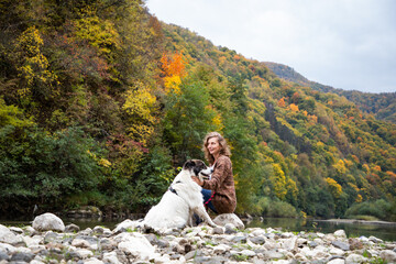 Naklejka premium woman with dog enjoying autumn nature by the lake