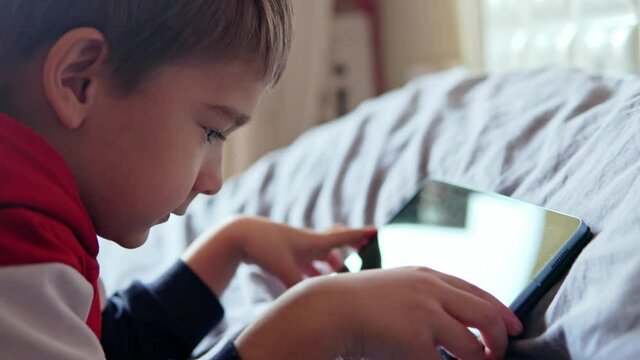 Closeup of a little boy playing his tablet. High quality 4k footage