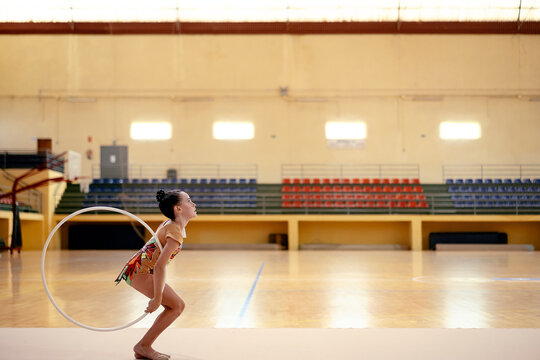 Gymnastics girl taking impulse to throw the hoop up
