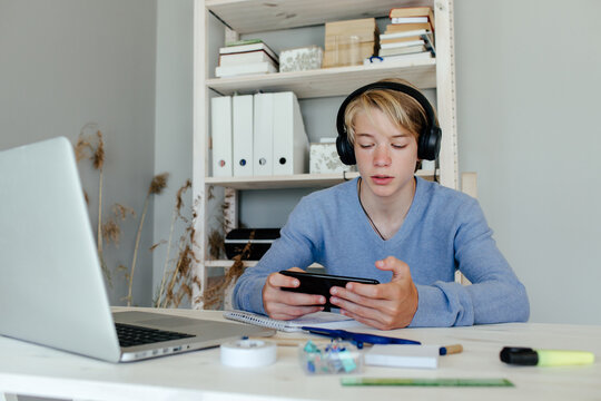 Kid playing game on phone instead of studying