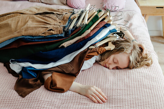 Lying woman pinned down by pile of clothes