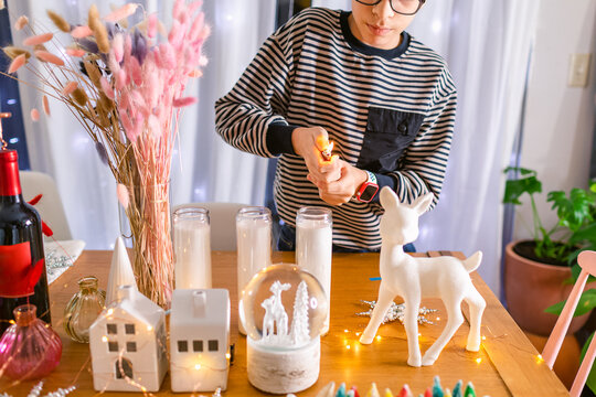 Boy igniting Christmas candle on table