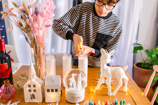 Boy igniting Christmas candle on table