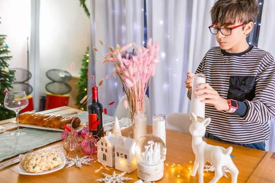 Boy igniting Christmas candle on table