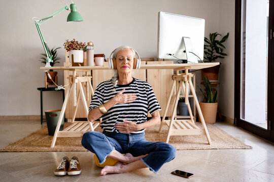Senior woman doing meditation at cozy office