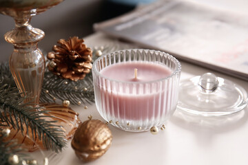 Aroma candle with Christmas decor on table in room