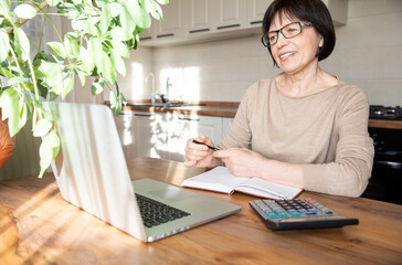 Obraz na płótnie Canvas Beautiful stylish elderly woman working at home with a laptop.