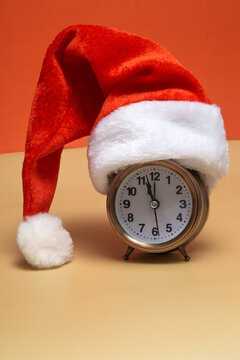 Alarm clock with santa hat on a colored background. New year shopping concept. Close up with copy space.