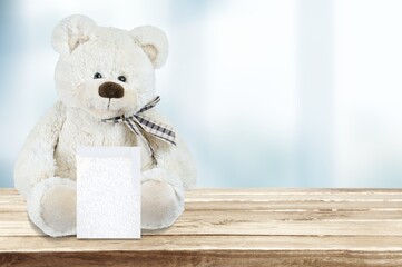 White toy bear holding card of question sign on a table
