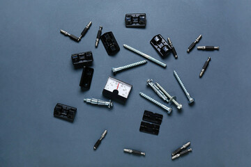 Analog thermostat, corner brackets, bolts and screws on dark background