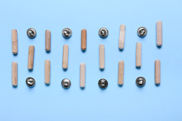 Dowels and metal bolts on color background