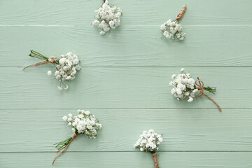 Frame made of beautiful gypsophila boutonnieres on color wooden background