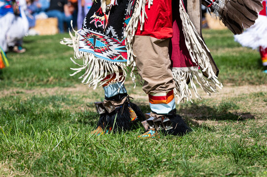 Photo of ankle cowbells and designed blanket as part of a Native American dancer's regalia at a public pow wow event.