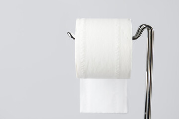 Modern holder with toilet paper roll on light background, closeup