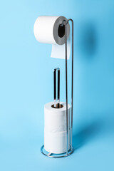 Modern holder with toilet paper rolls on blue background