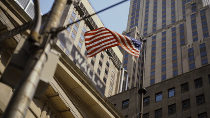Wall Street sign with American flags in the background, shot in the heart of the business world in...