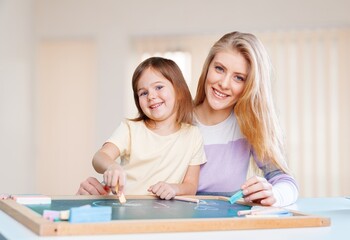 Obraz premium Smiling mother with little child drawing, spending leisure time together