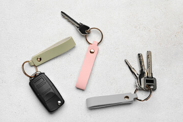 Keys with leather keychains on light background