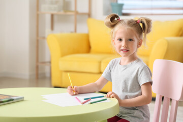 Cute little girl with ponytails drawing at table in living room