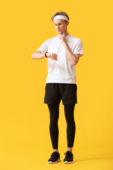 Sporty male runner checking pulse on color background