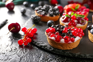 Board with tasty berry tart on dark background