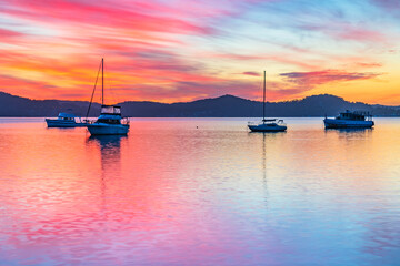 Sunrise waterscape with boats, reflections and high cloud