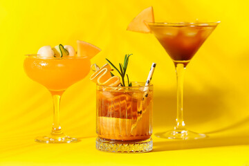 Glasses of different melon cocktails on yellow background