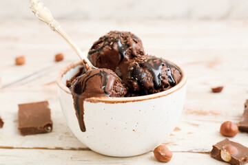 Bowl of tasty chocolate ice cream on white wooden background