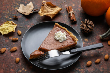 Plate with piece of tasty pumpkin pie on grunge background