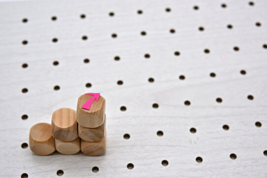 On the edge of a white perforated board, there is a sticky note in the shape of an arrow. Copy space available.