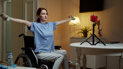 Fototapeta na wymiar A disabled woman is making an exercise with dumbbells on the Internet