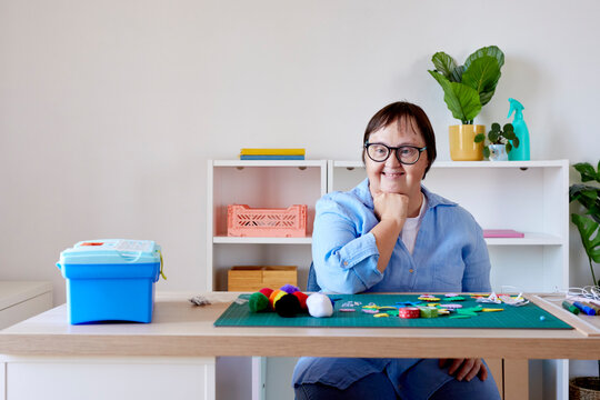 Happy craftswoman with Down syndrome sitting at table