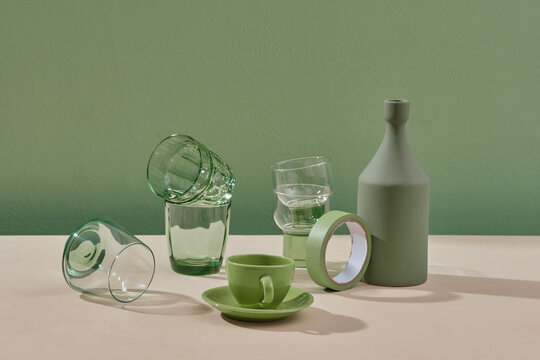 Different glassware and vase on green background.