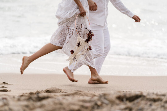Barefoot newlyweds running on seashore