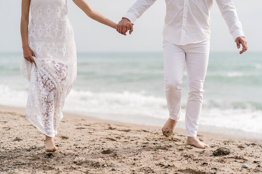 Newlywed couple holding hands on the beach